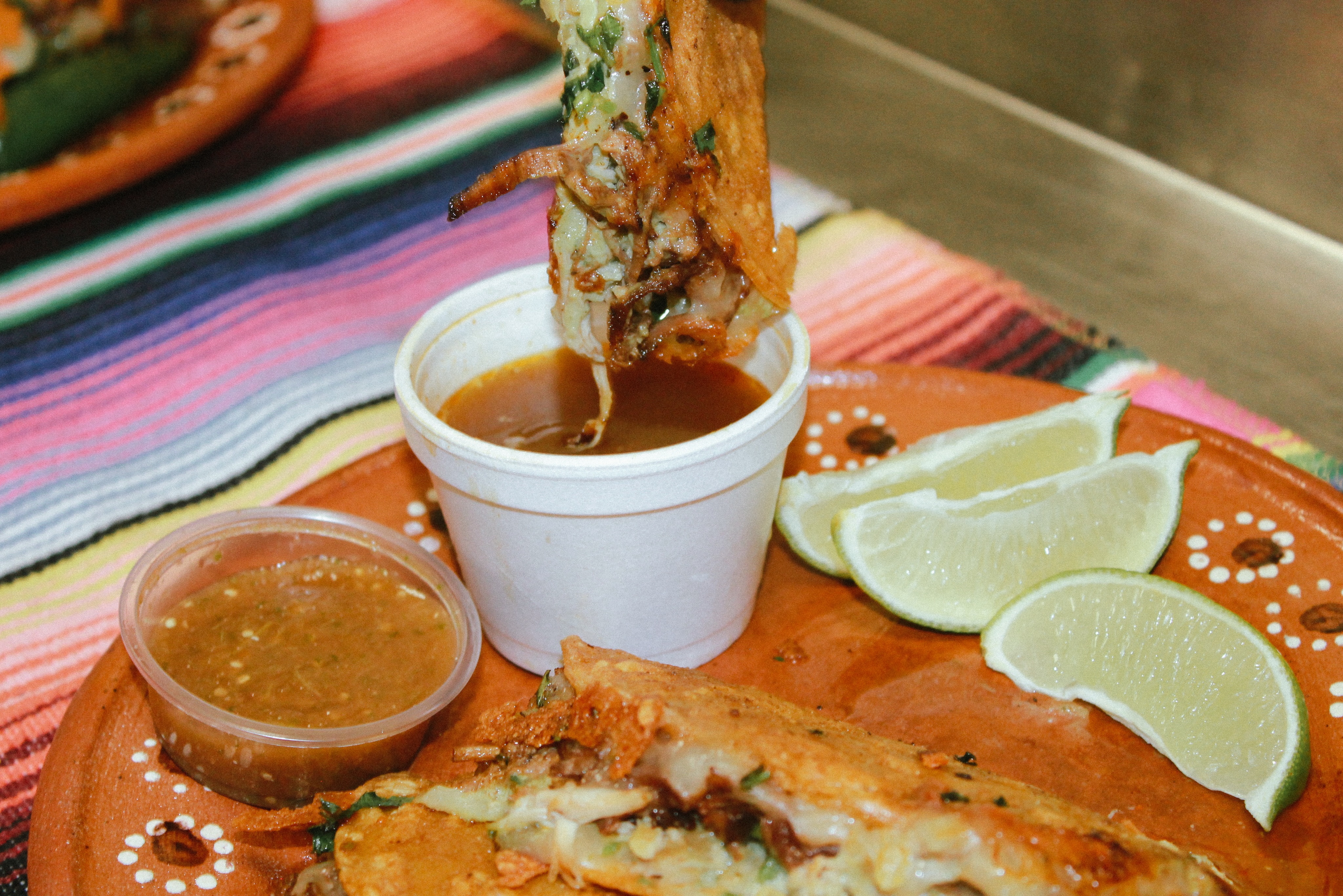 Chef Tastebudz quesabirria dipped in consommé, with salsa and lime